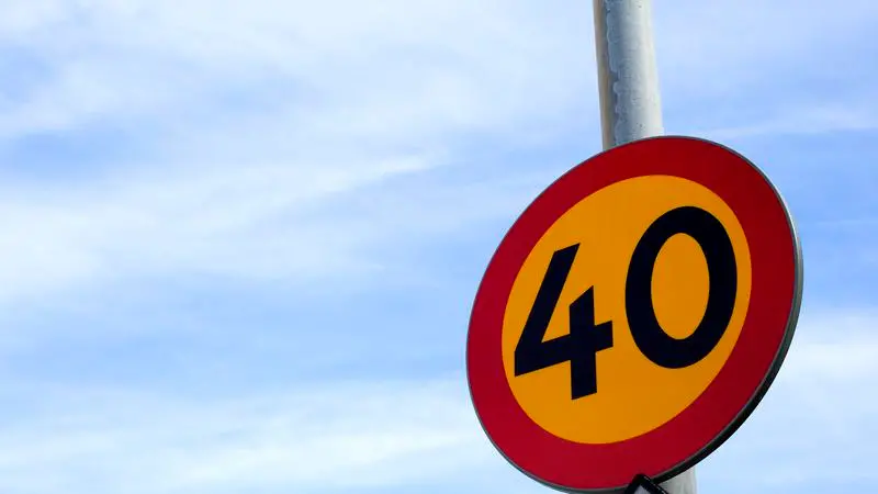 Rund 40-vägskylt på stolpe med blå himmel bakgrunden