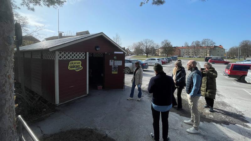 Rött miljöhus med med skylt Gör det inte svårare än det är, 5 personer står utanför.