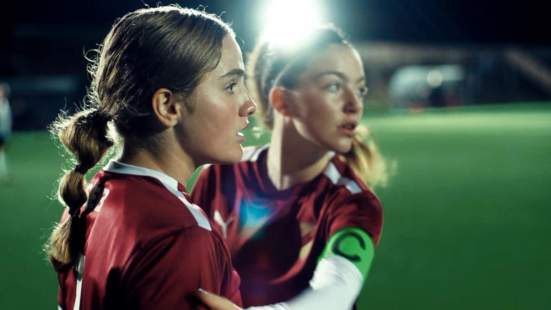 Två unga kvinnliga fotbollsspelare på upplyst fotbollsplan
