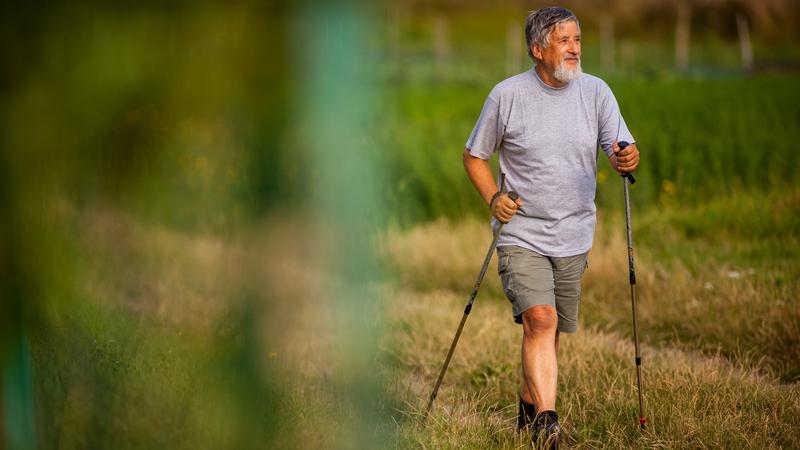 Man går stavgång på äng
