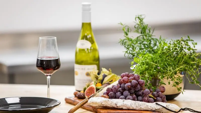 Ett glas vin och en bricka med chark och frukt