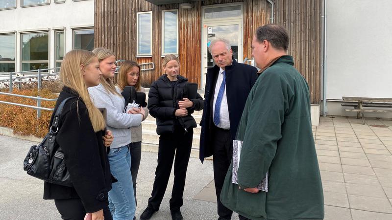 Talmannen och landshövdningen står utanför Wisbygymnasiet och samtalar med några elever.