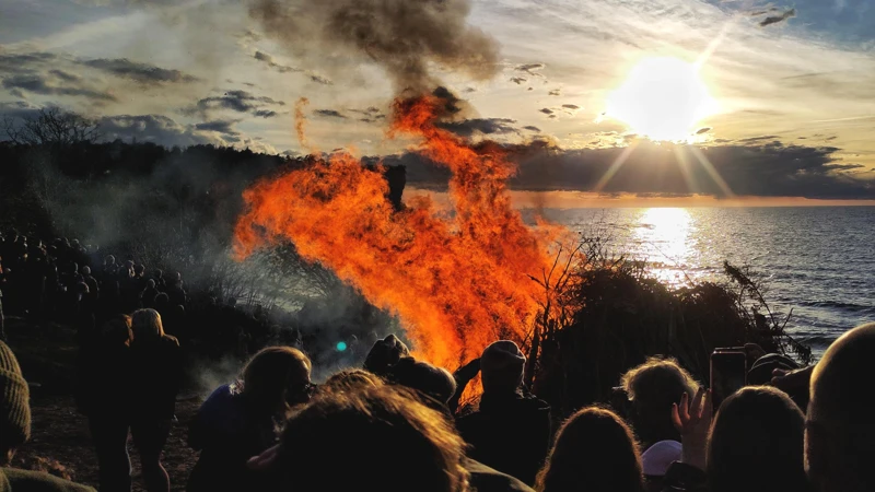 En stor grupp människor som tittar på en valborgseld.