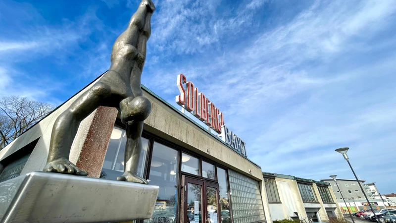 En staty av en person som står på händer utanför en byggnad.