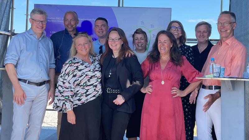 9 glada seminariedeltagare på en scen