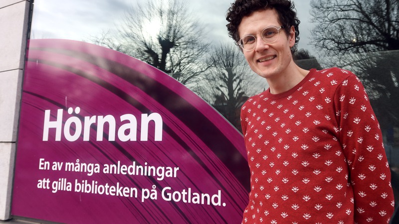 Henrik Ramberg står framför Almedalsbibliotekets skyltfönster med texten "Hörnan: En av många anledningar att gilla biblioteken på Gotland.
