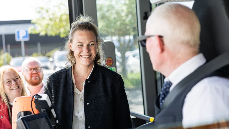 Glada resenärer väntar på att kliva in bussen, chaufför