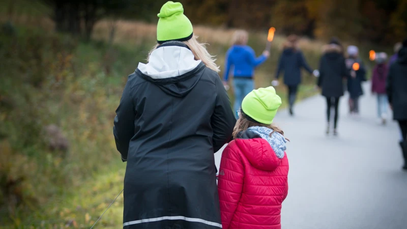 En kvinna och ett barn går längs en väg.