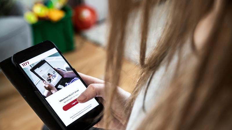 En person är på webbplatsen 1177.se med sin mobiltelefon.