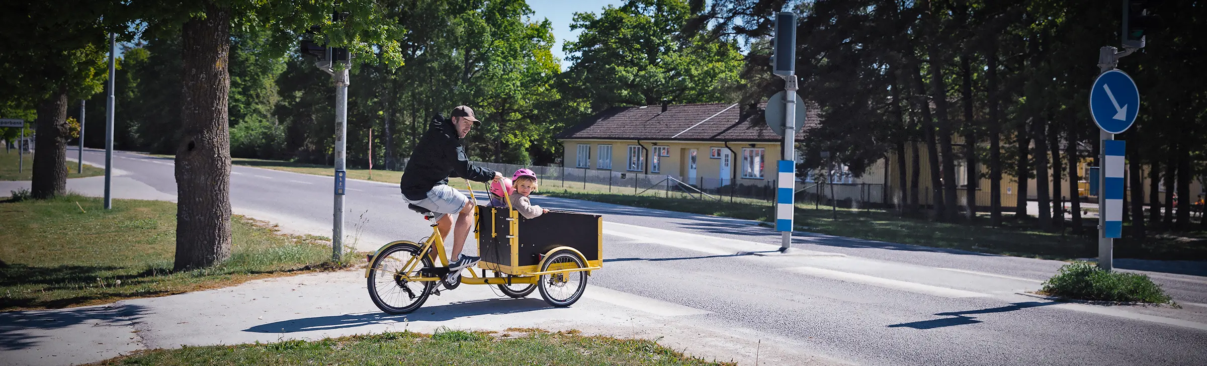 Man skjutsar barn på en cykel vid ett övergångsställe