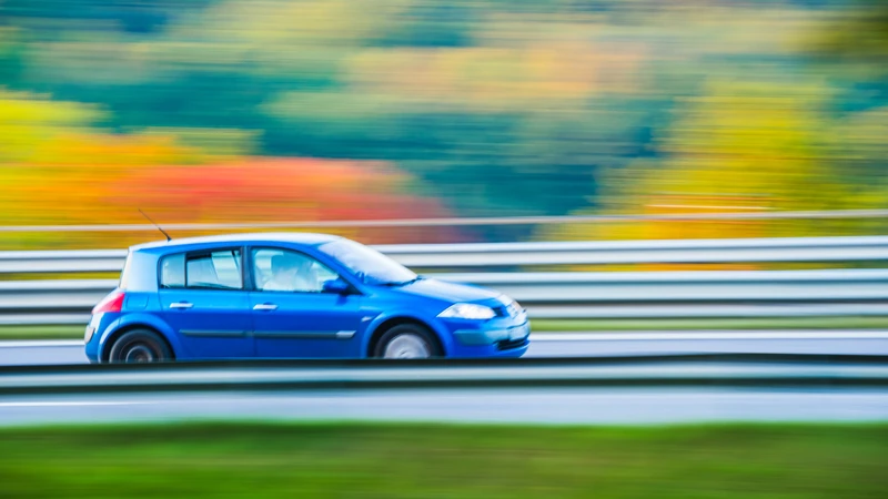 En liten blå bil som kör längs en väg.