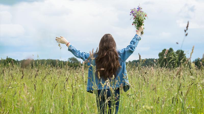 En kvinna står på ett fält och håller i en blombukett