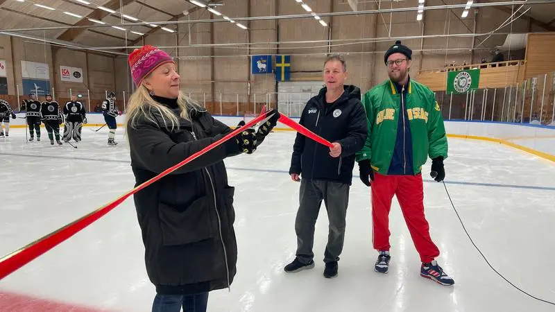 Kvinna klipper rött band i en ishall