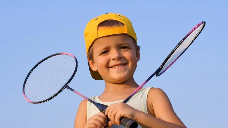 Pojke med keps och två badmintonrackets
