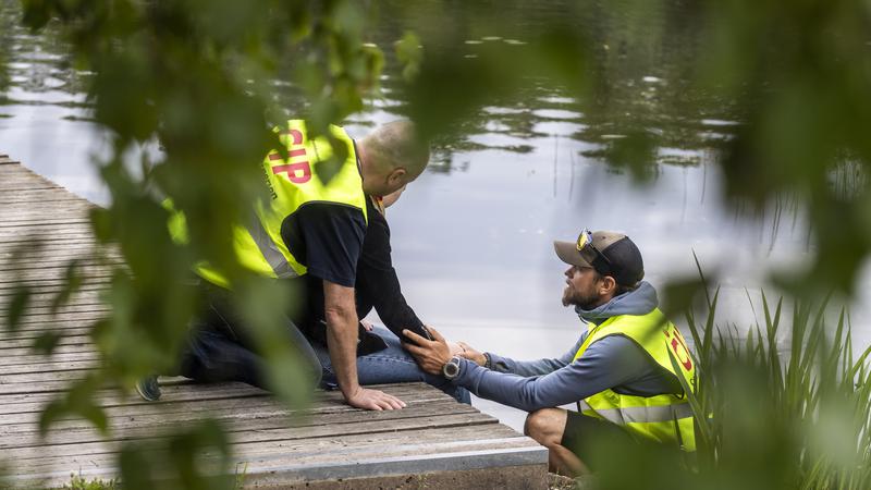 Två personer med reflexväst tar hand om en person vid en brygga.