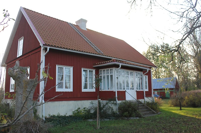 Ett rött trähus med vita fönster och ett rött tak med en skorsten.