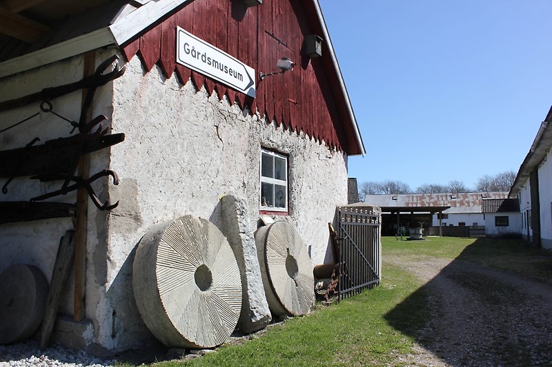 På den rödvita stugan med ett litet fönster finns det en skylt med Gårdsmuseum på