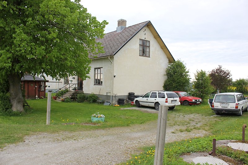 Beige landshus med flera parkerade bilar