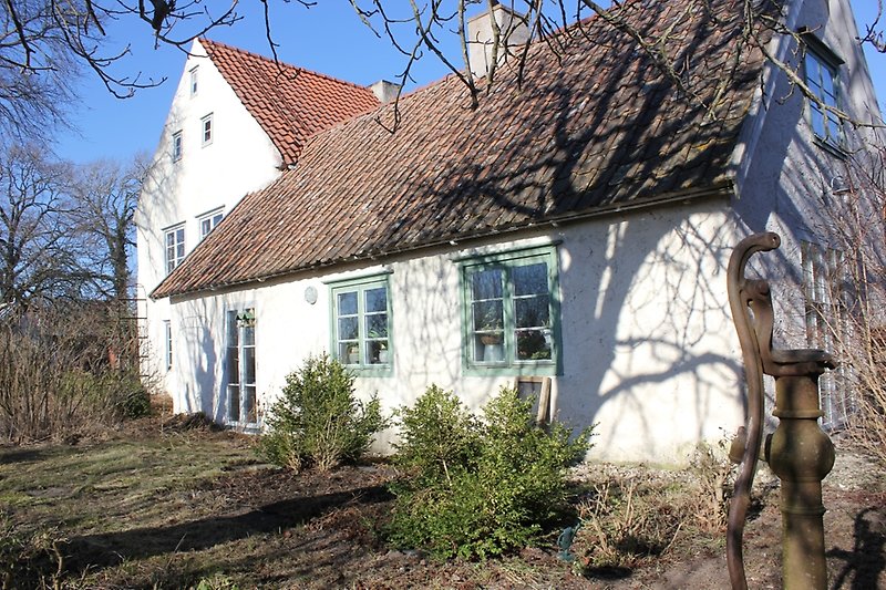 Ett vitt hus med gröna och blåa fönster och ett orange tegeltak.