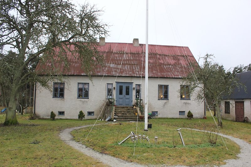 Ett vitt hus med blåa fönster, en blå ytterdörr och ett rött tak.