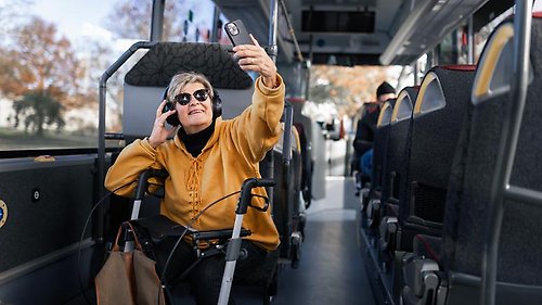 En kvinna sitter på en buss och tar en selfie