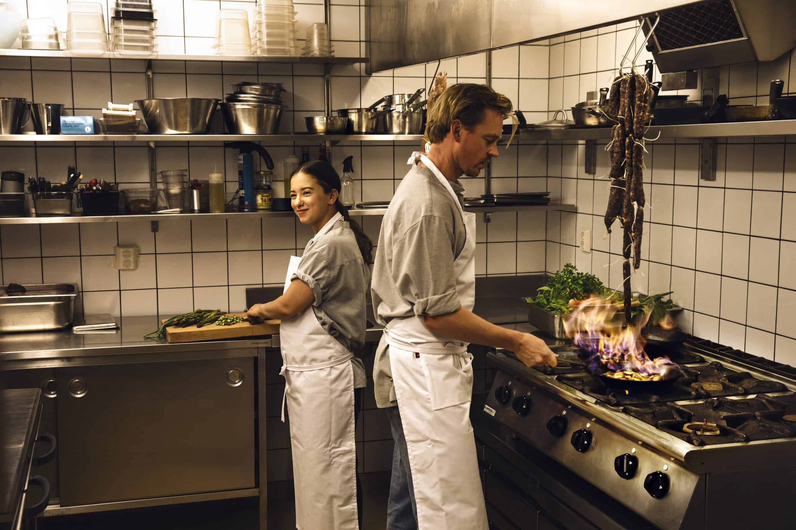 kvinna och man lagar mat i restaurangkök