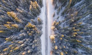snötäckt landsväg omgiven av skog sedd uppifrån