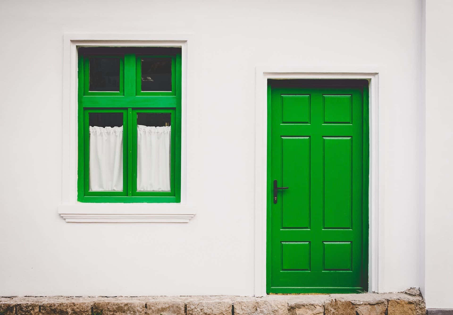 Vit fasad med grön dörr och grön fönsterkarm
