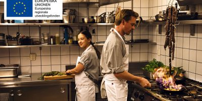 Kvinna och man som lagar mat i restaurangkök.