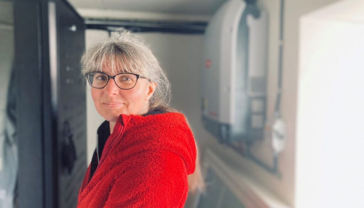 Kvinna står framför solcellsbatteri och växelriktare