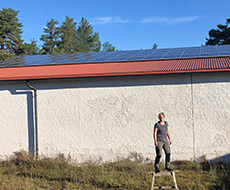 Man framför idrottshall med solceller på tak