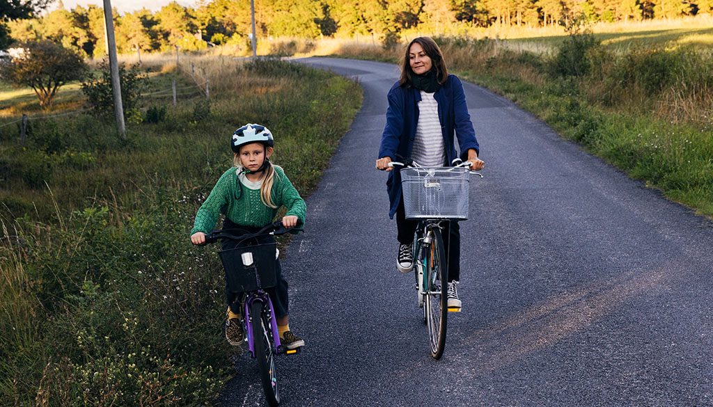 Barn och kvinna som cyklar på landsväg