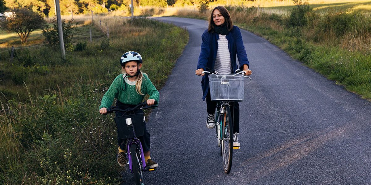 Barn och kvinna som cyklar på landsväg