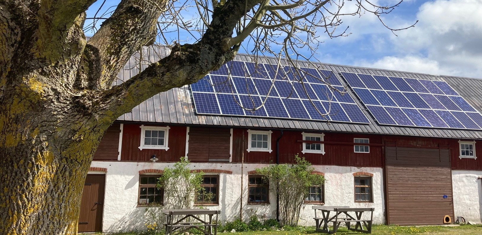 Äldre ladugård med solpaneler på taket.