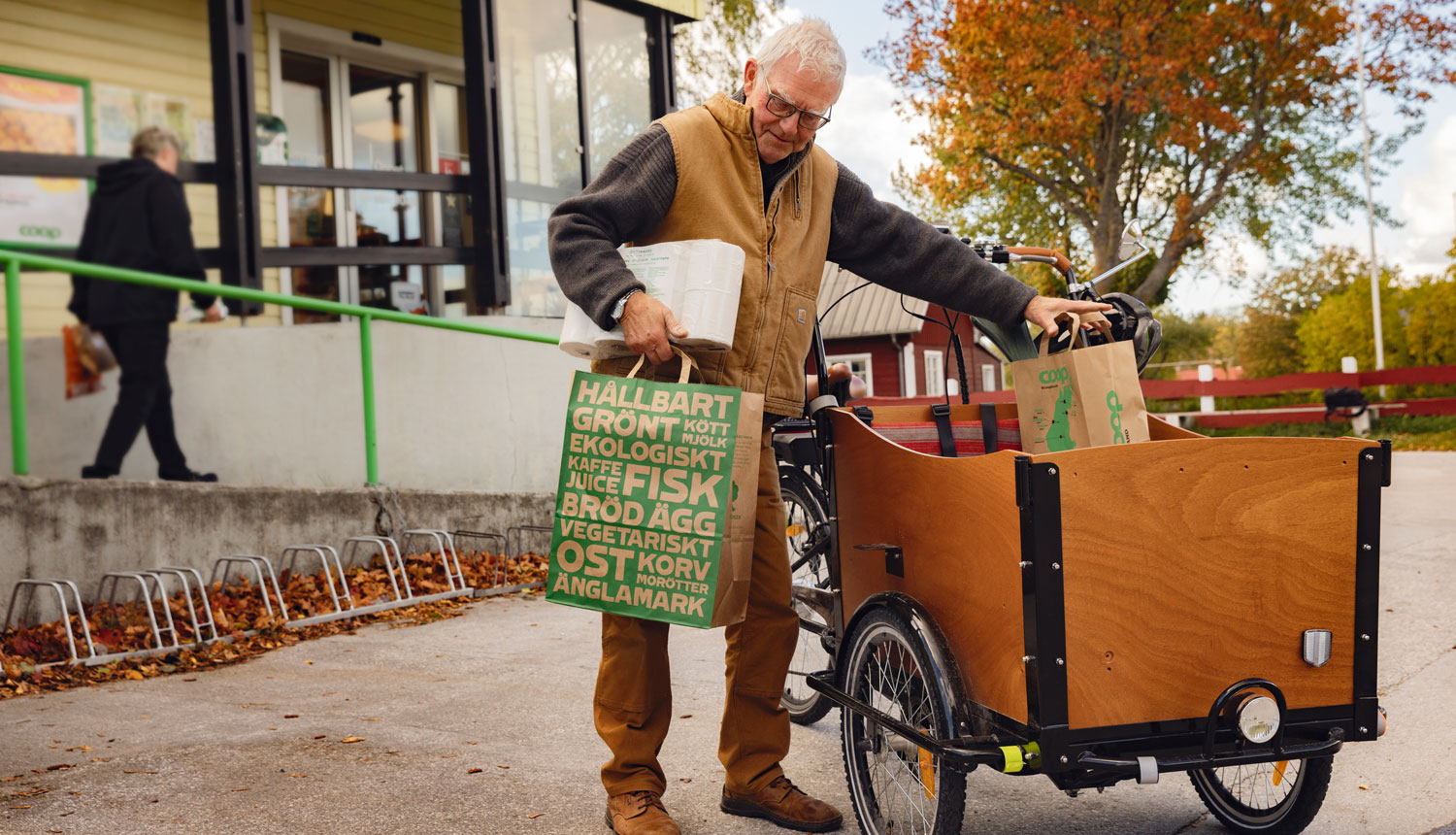 äldre herre lastar lådcykel med matvaror mobiitetl