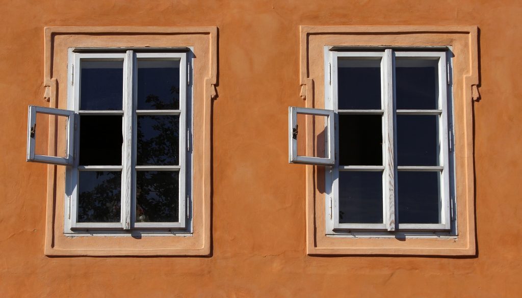 två fönster med spröjs på en orangefärgad husfasad