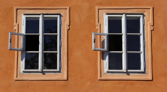 två fönstrar med spröjs på en orangeföärgad putsad fasad