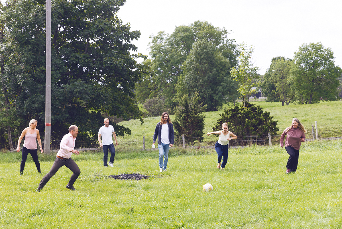 ett antal personer spelar fotboll på en grön sommaräng