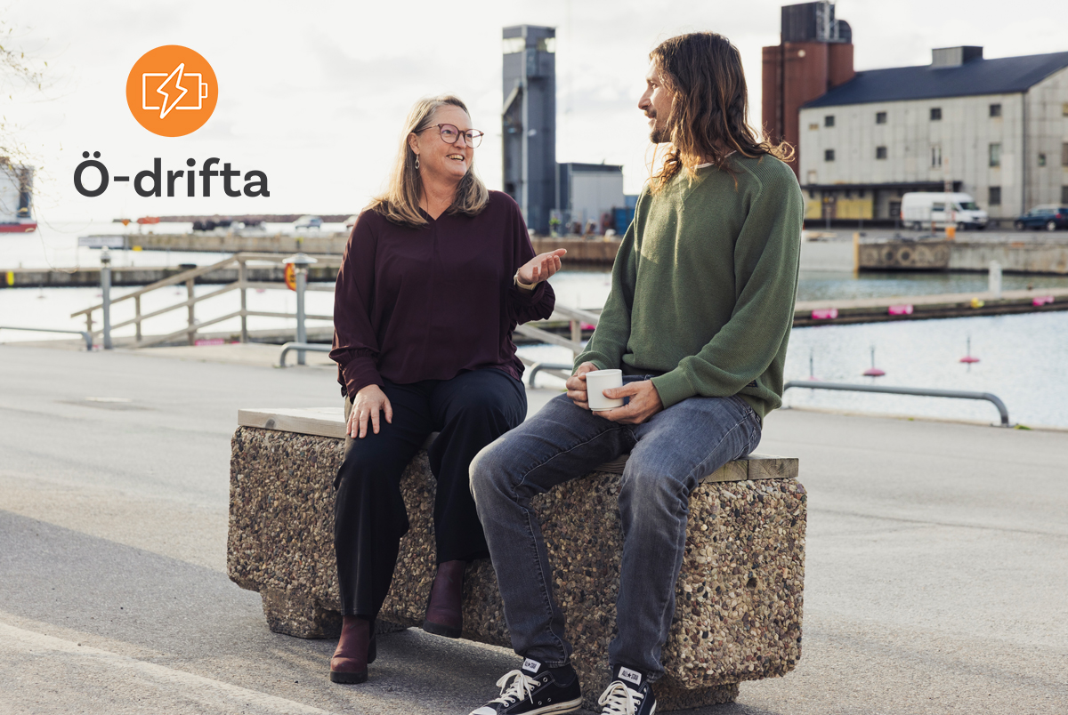 två personer sitter på en bänk i Visby hamn och pratar. Logo Ö-drifta uppe i vänster hörn.